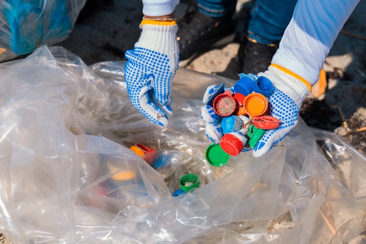 A gloved hand drawing coloured plastic caps from a bg.