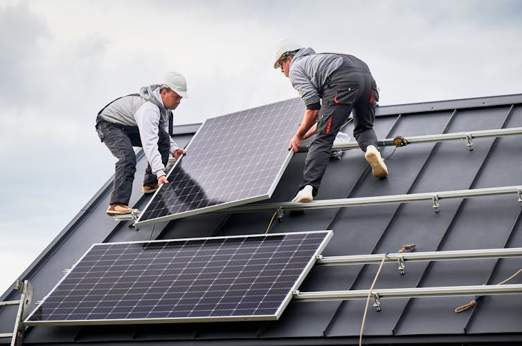 Two people installing a solar panel.